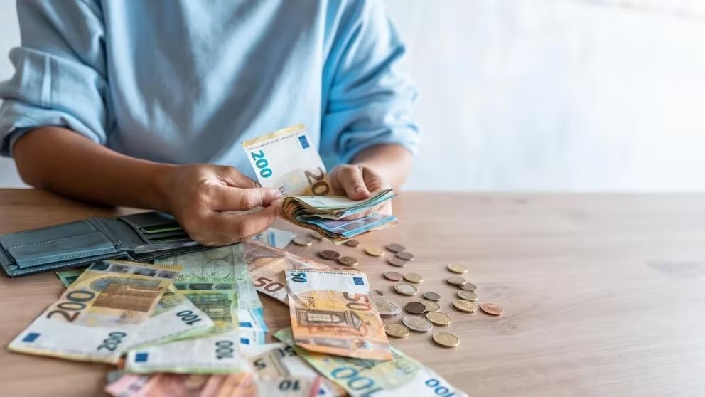 Una mujer cuenta billetes y monedas